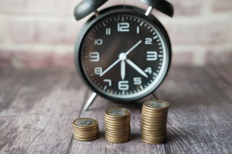 Stacked coins and a classic alarm clock