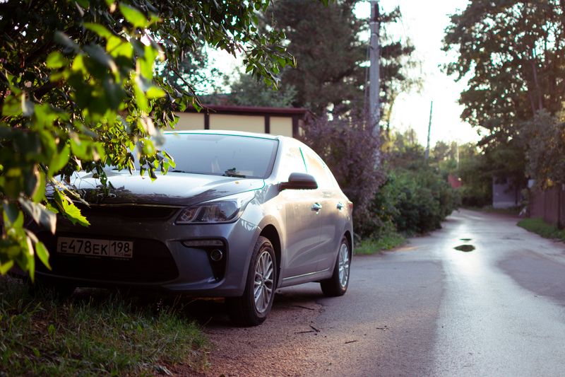 A car parked by a quiet road in a leafy village setting, captured at sunset