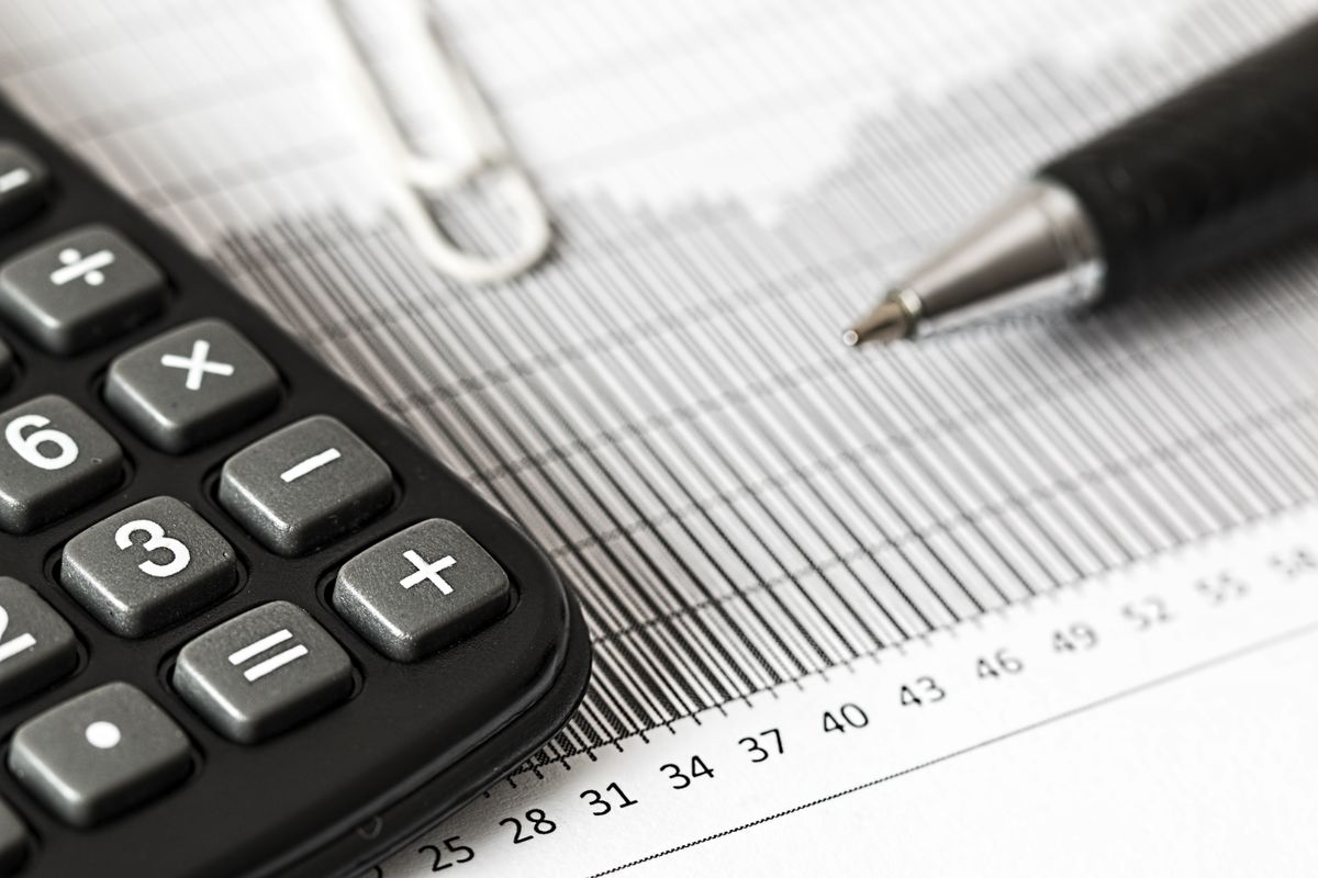 Close-up of a calculator and pen on a bar graph
