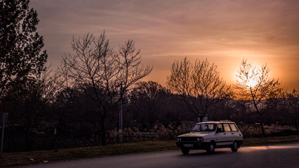 A vintage car traveling on a scenic road