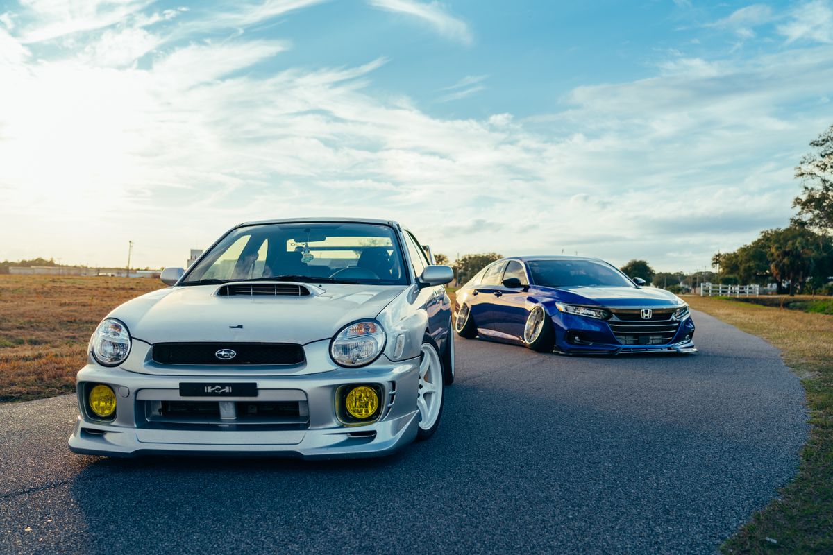 Stylish modified cars parked on a scenic road during sunset