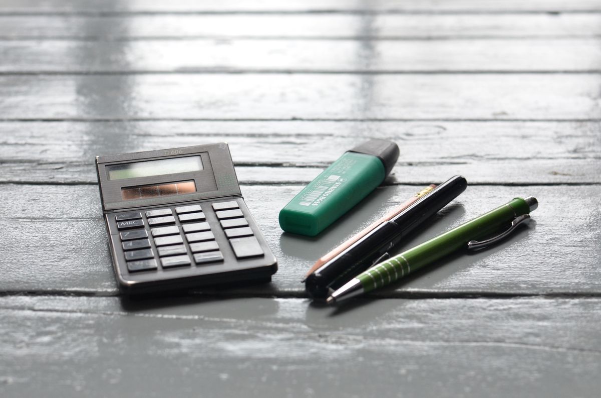 High angle of small electronic calculator green marker and pens on wooden table in office