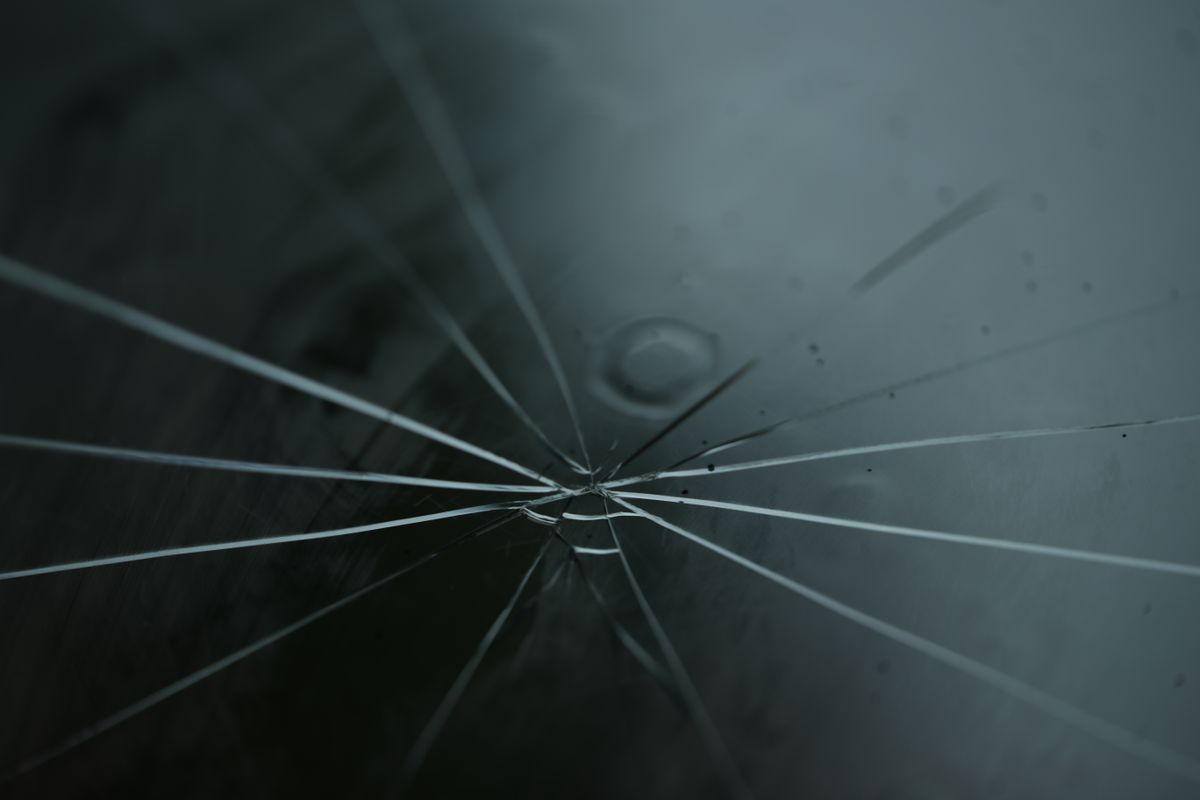 A detailed shot of cracked glass with radiating lines on a moody background