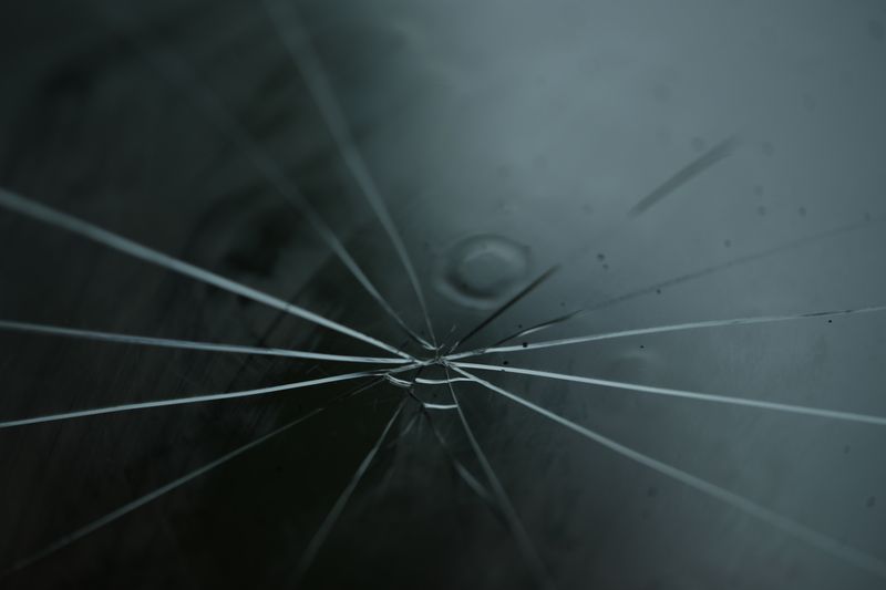A detailed shot of cracked glass with radiating lines on a moody background