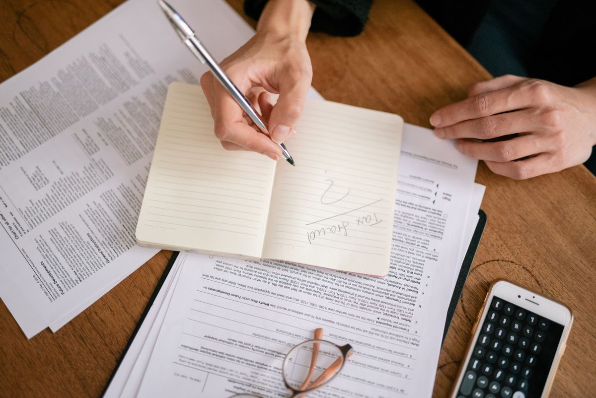 Hands writing notes next to a smartphone