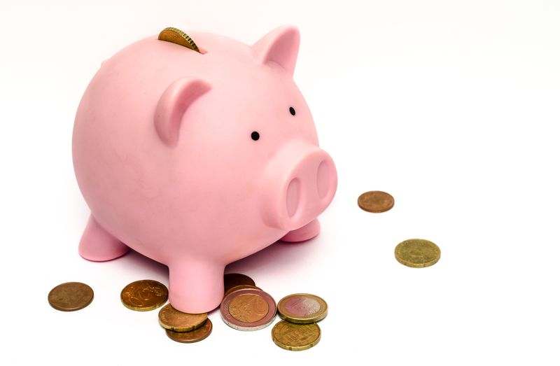 A pink piggy bank surrounded by scattered coins